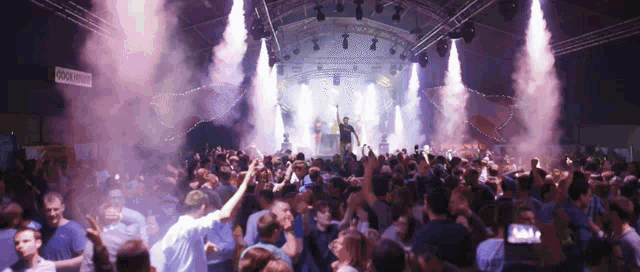 a crowd of people dancing at a concert with a sign that says cool drinks in the background