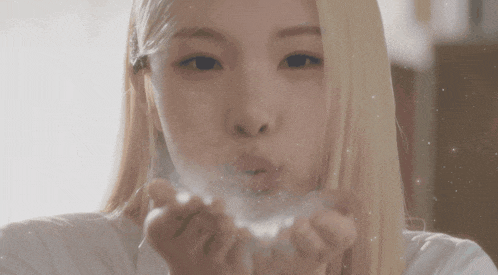 a close up of a woman blowing powder out of her hands