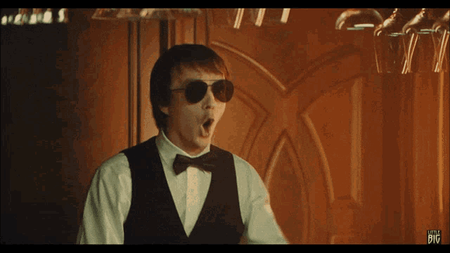 a man in a tuxedo and bow tie has a little big sticker on his chest