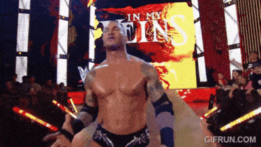 a shirtless wrestler stands in front of a screen that says " in my sins "