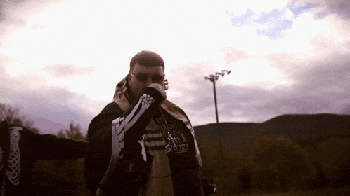a man wearing a skeleton hoodie stands in front of a purple sky