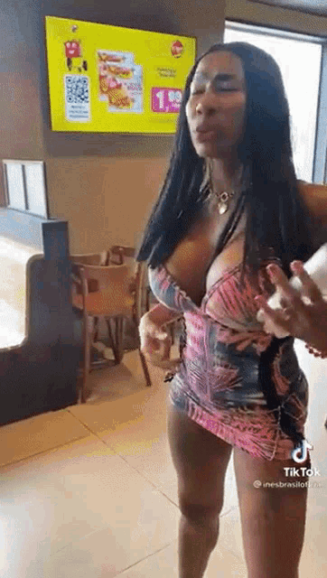 a woman in a very short dress is standing in a restaurant talking to a man .