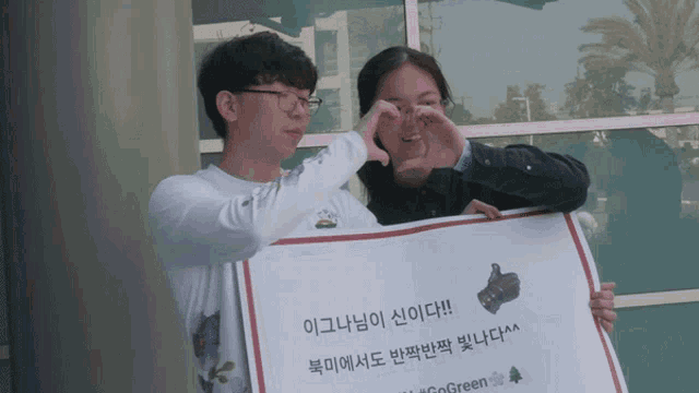 a man and a woman are holding a sign that says go green