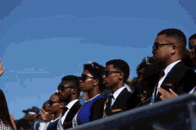 a group of people wearing suits and sunglasses stand in a row