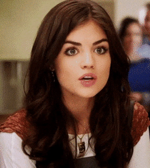 a woman with long brown hair is making a surprised face .