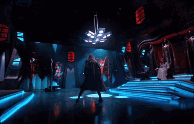 a woman in a white dress sits on a throne in a dark room with blue lights