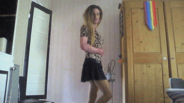 a woman in a leopard print top and black skirt is standing in a room