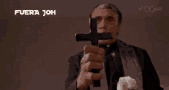 a man in a suit is holding a cross in front of a sign that says fuera joh fuera joh