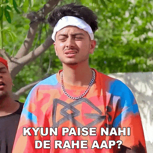 a young man wearing a headband and a necklace says " kyun paise nahi de rahe aap "