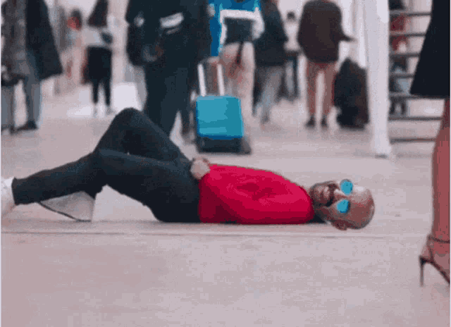 a man is laying on the ground wearing sunglasses and a red shirt