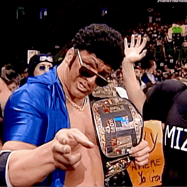 a man in a blue shirt is holding a wrestling belt