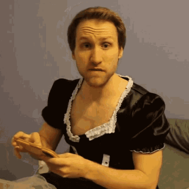 a man in a maid costume holds a cell phone