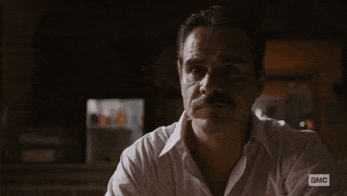 a man with a mustache is wearing a shirt that says ' амс ' on the bottom