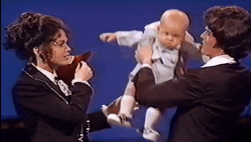 a woman is holding a baby in her arms while a man holds it in his arms .