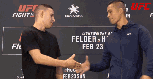 two men shaking hands in front of a ufc sign