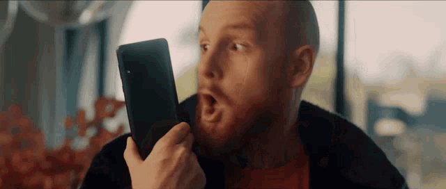 a man with a beard is holding a cell phone in his hand