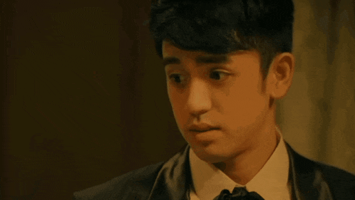 a young man in a tuxedo and tie looks at something