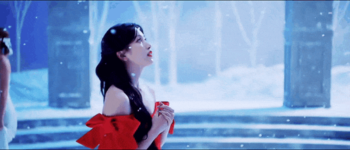a woman in a red dress is standing in a snowy forest .