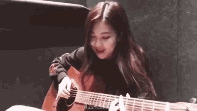 a young girl is playing an acoustic guitar in a room .
