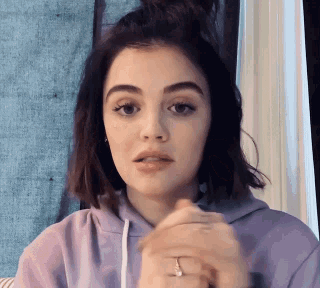 a woman wearing a purple hoodie and a diamond ring
