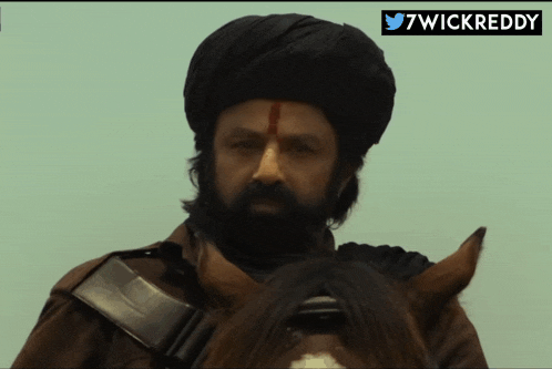 a man wearing a turban is riding a horse with a twitter logo behind him