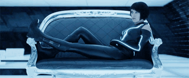 a woman is laying on a couch in a futuristic outfit