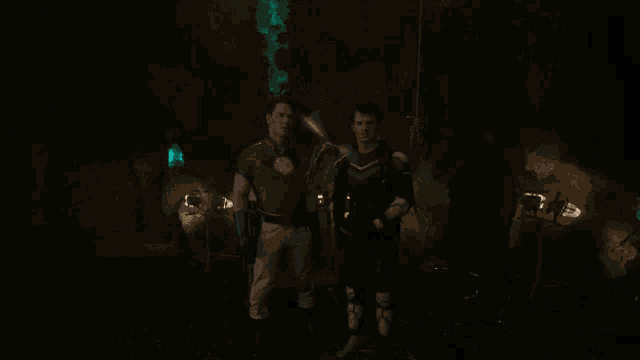 a man in a red shirt stands in a dark room