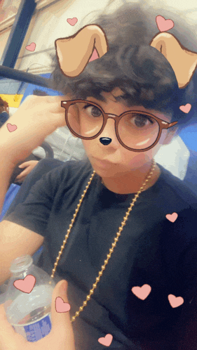 a person wearing glasses and a necklace holds a bottle of water