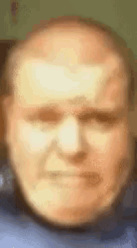 a close up of a man 's face with a blurred background making a funny face .