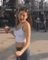 a woman in a white crop top and shorts is standing on a sidewalk .