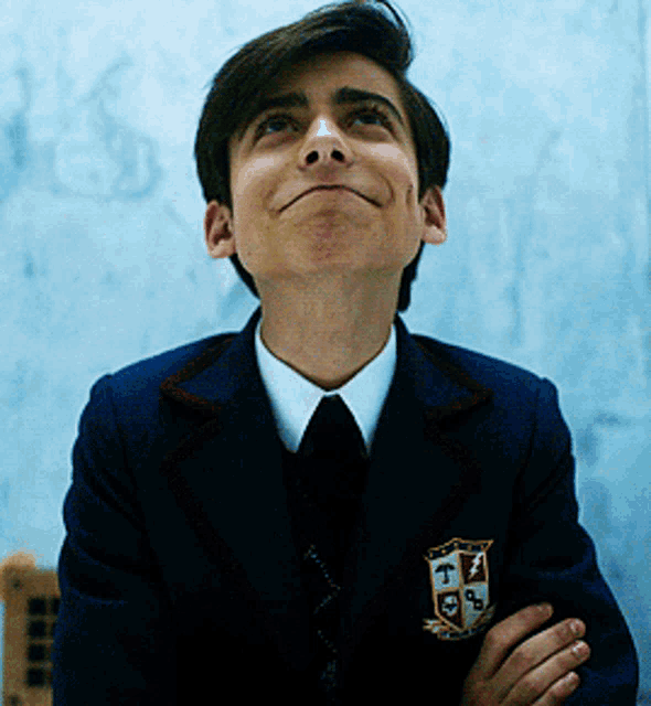 a young boy wearing a suit and tie with a crest on his jacket