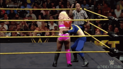 a woman in a pink and blue outfit is wrestling a man in a blue suit ..