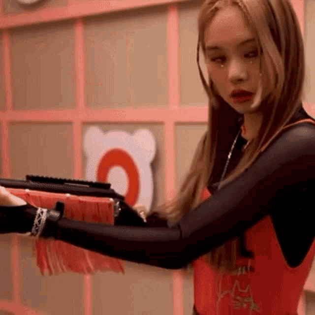 a woman in a red tank top is holding a gun in her hand .