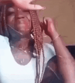 a woman with braids is making a funny face while wearing a mask .