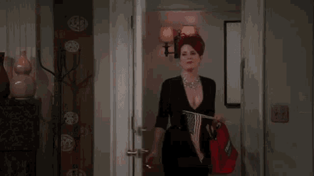 a woman in a black dress is holding a red bag and an american flag .