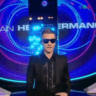 a man wearing sunglasses and a suit is standing in front of a sign that says armani