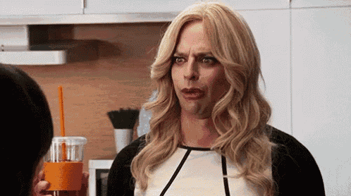 a man in a wig is holding a cup of orange juice and making a face .