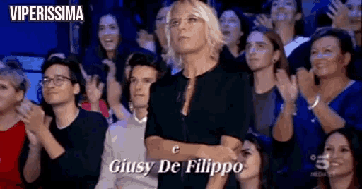 a woman is standing in front of a crowd applauding .