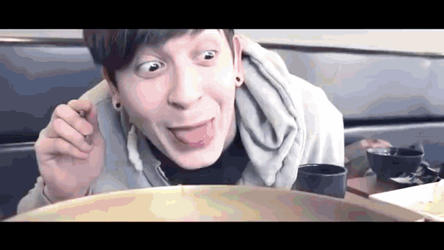 a man is making a funny face while eating food from a large bowl .