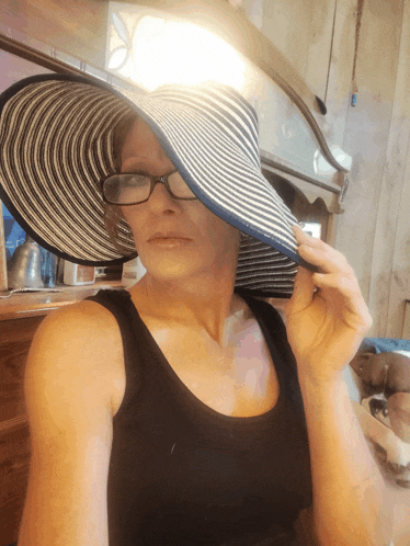 a woman wearing glasses and a striped hat looks down