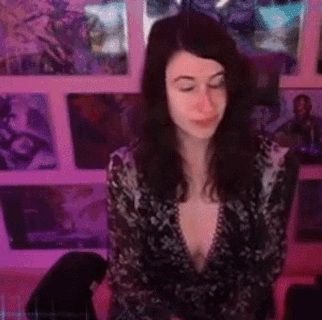 a woman in a plunging neckline top is sitting in front of a wall of pictures