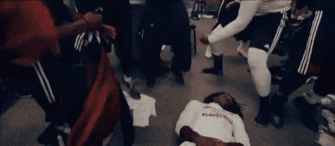 a man is laying on the floor in a locker room surrounded by people