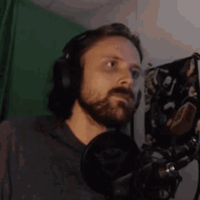 a man with a beard is standing in front of a microphone and waving his hands .