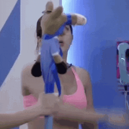 a woman in a pink top is holding a stuffed animal