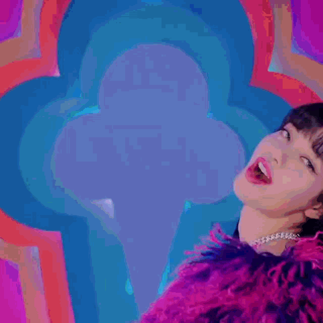 a woman in a pink fur coat and black tights is dancing in front of a purple and blue background .