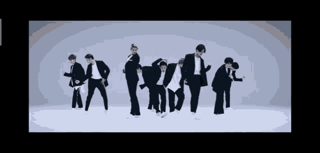 a group of young men in suits and white shirts are dancing