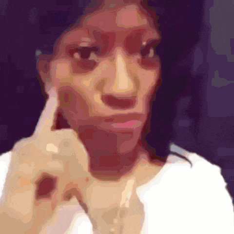 a woman in a white shirt is making a funny face with her finger on her ear