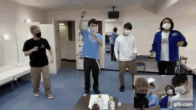 a group of men wearing masks are dancing in a room .