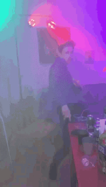 a blurry picture of a man in a room with purple and green lights