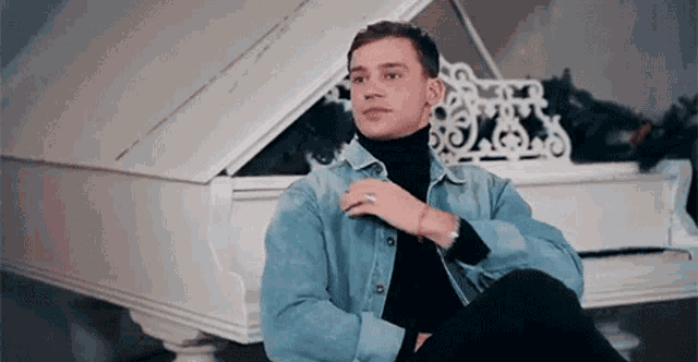 a young man is sitting in front of a white grand piano .